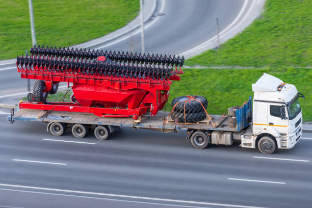 istock Transportation of large agro-complex machines for cultivating and sowing crops on long trailers by trucks along the highway in the city. 1225071765