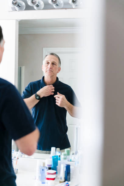 istock Standing in bathroom, senior man adjusts buttons on shirt 1225071904