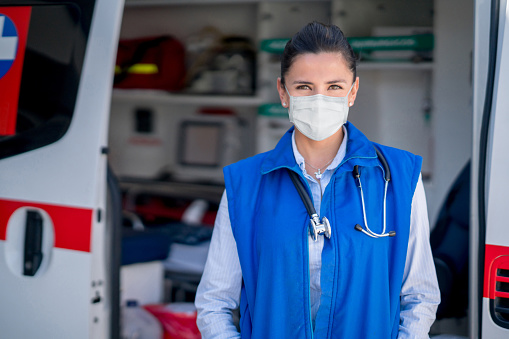 Paramédico trabajando en una ambulancia durante la pandemia COVID-19 y usando una mascarilla photo