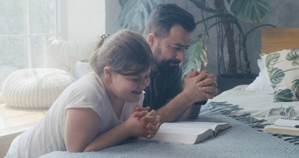 istock Father and daughter praying together 1225079127