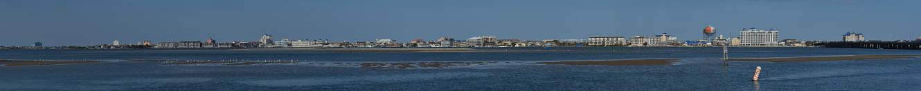 Ocean City Maryland bayside skyline panorama from across Assawoman Bay with blue water, blue sky and sea birds flying about in the breeze