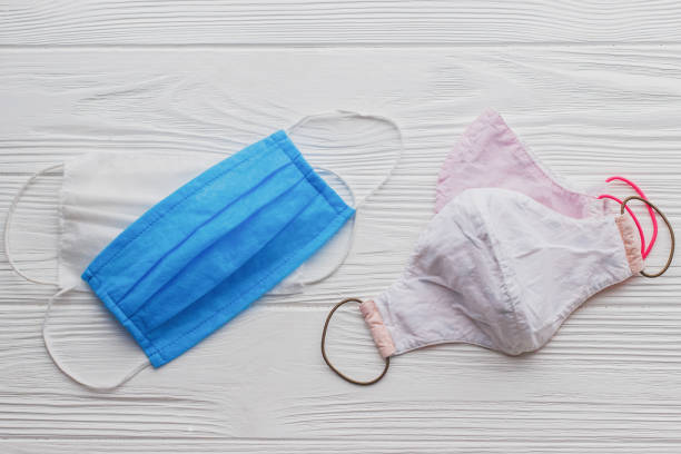 istock Reusable face masks and single use medical masks on white wooden background flat lay. Zero waste lifestyle during virus outbreak. Disposable mask and handmade textile mask 1225082802