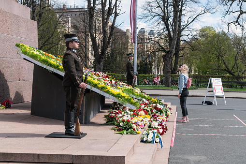 Riga, Latvia – May 4, 2020: Guard of honor. And flowers are put by the monument as it's the day when 20 years ago Latvia proclaimed its independence from the USSR. There are so few people in the streets because of Covid-19 quarantine.