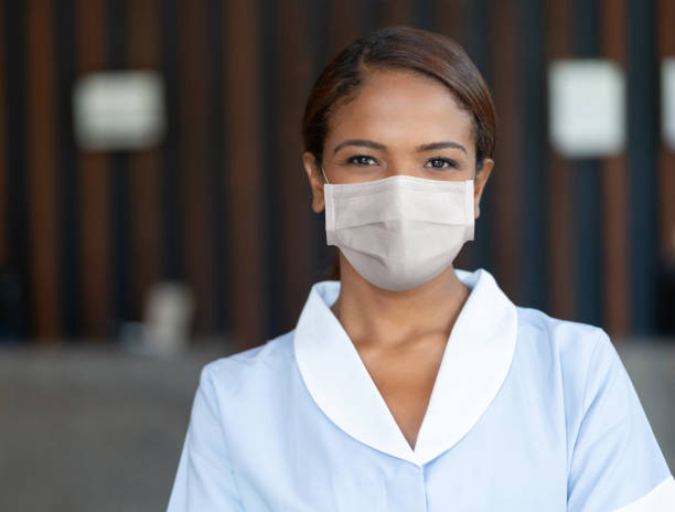 Maid wearing a facemask to avoid the spread of coronavirus while working at a hotel Portrait of an African American maid wearing a facemask to avoid the spread of coronavirus while working at a hotel - Pandemic lifestyle concepts housekeeping staff photos stock pictures, royalty-free photos & images