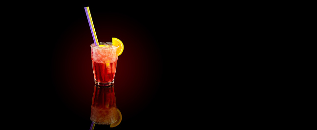 Red cocktail with orange slice, summer cold drink over black background