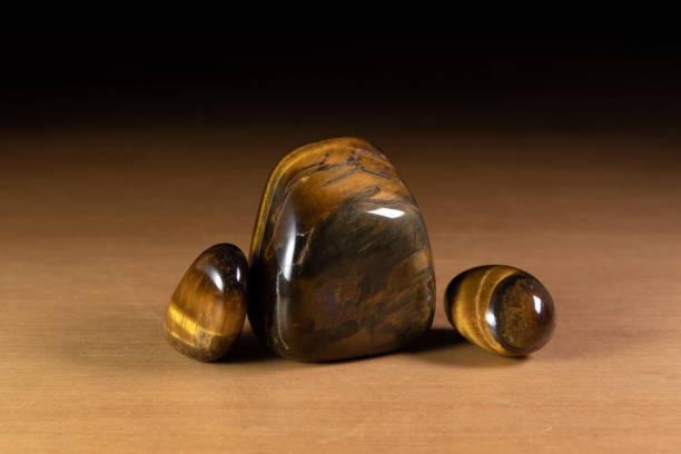 Polished tiger eye chatoyant gemstones over a wooden table. Specimens from Spain