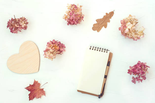 istock Workspace with notebook on white background. Autumn composition with dry flowers and leaves. Flat lay, top view. 1225092682