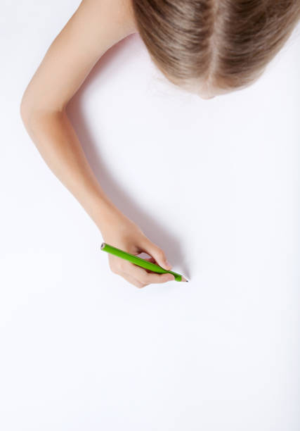 Little girl drawing with crayons on a paper roll sticked on a wall