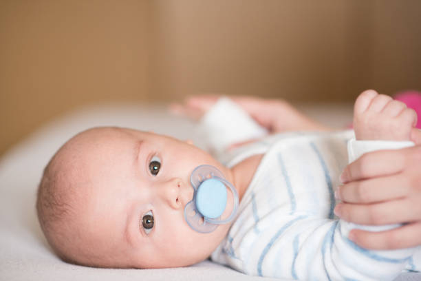 istock Close up baby boy with pacifier lying down on a bed and looking at camera 1225099349