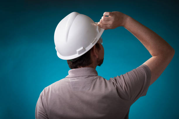 istock Construction worker with beard holding white safety helmet seen from the back with protective glasses on 1225100488