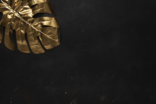 istock Creative layout with gold tropical palm leaves on black background. Minimal summer abstract pattern. 1225102422