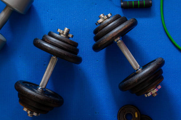 istock Two metal dumbbells in centre frame surrounded by other exercise equipment 1225104713
