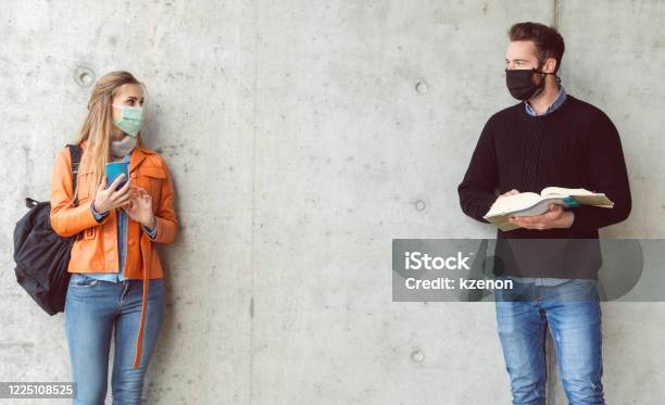 Due Studenti In Piedi A Distanza Sociale Indossando La Maschera Facciale - Fotografie stock e altre immagini di Distante