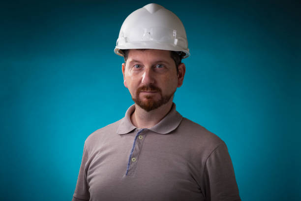 istock Construction worker with beard and white safety helmet looking into the camera with protective glasses on his hardhat 1225109695