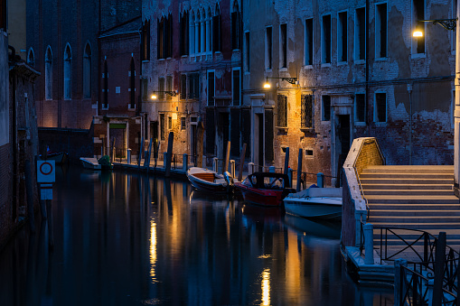 Venedig bei Nacht mit Gondeln im Vordergrund und klassischer Laterne