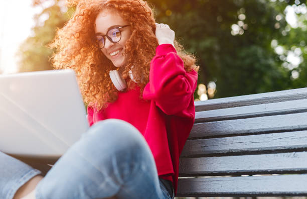 istock Delighted woman using laptop in park 1225115758