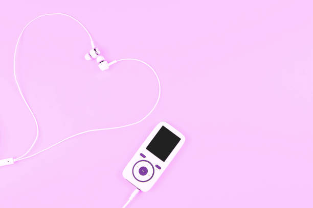 White music player with earphones laying in a shape of a heart on pastel purple background. Concept of love with music. Place for text, flat lay.