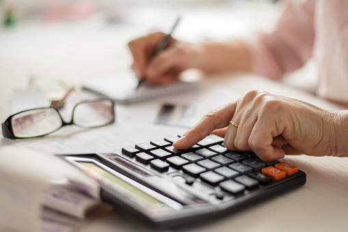 Concepto de cálculo de la pensión, viejas manos contando las finanzas en una calculadora de la casa, primer plano photo