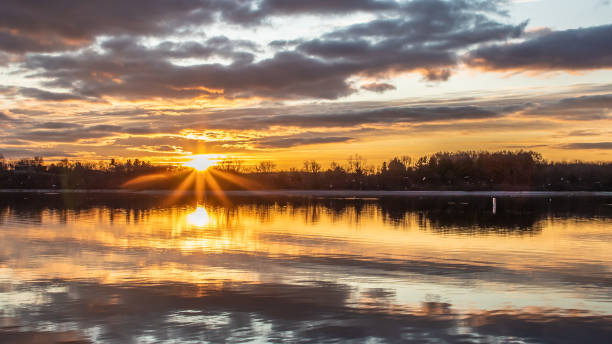 The sun bursts through the clouds at dawn on Blue Marsh Lake in Berks County, PA stock photo