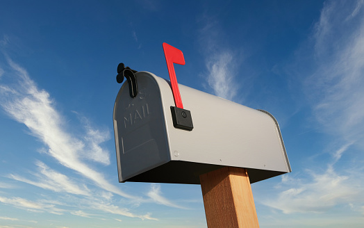 A mailbox painted with a United States flag and a red wooden bird perched on top of it in a Texas residential neighborhood on  January 2024. To the right is an American and Texas flag on a flagpole. Selective focus.