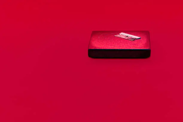 With plenty of copy space, a dirty razor blade sits on a drink coaster in the top right of the image. Possible uses include for illegal narcotics such as cocaine use or other drugs but without showing any powder or further paraphernalia. Also, although edgy, suicide could be a use for this moody, red background shot.