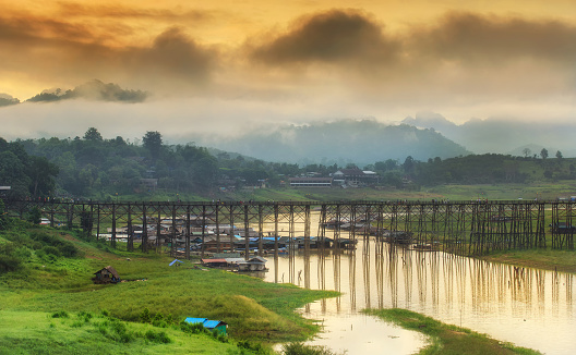 landscape of Wooded bridge over the river at sunrise (Mon Bridge) in Sangkhlaburi District, Kanchanaburi, Thailand.