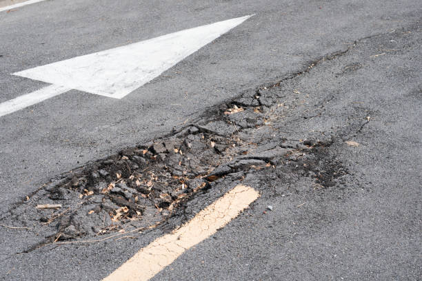 壊れたアスファルト道路、危険なひび割れた道路が崩壊 - pot hole ストックフォトと画像