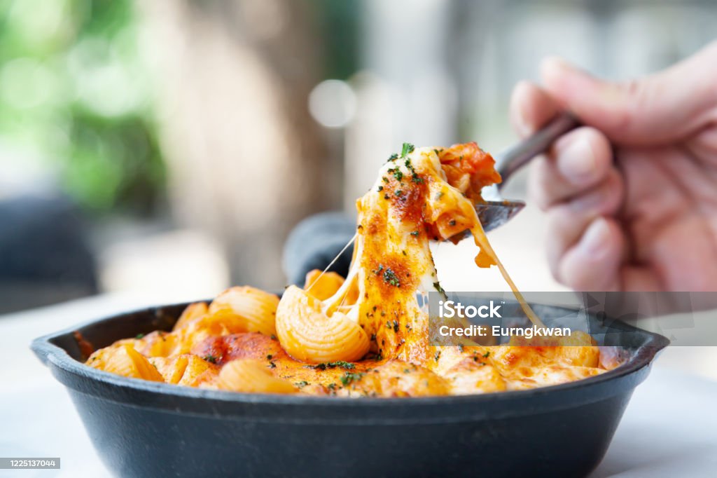 Baked macaroni and cheese with fresh tomato sauce Baked macaroni and cheese with fresh tomato sauce served on hot pan Macaroni and Cheese Stock Photo