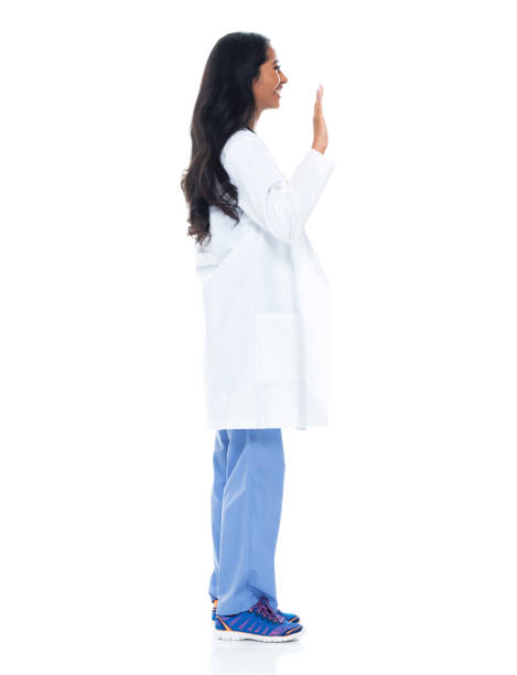 etnia latinoamericana e ispanica giovani donne medico in piedi di fronte a sfondo bianco indossando camice da laboratorio - donna profilo braccia alzate foto e immagini stock