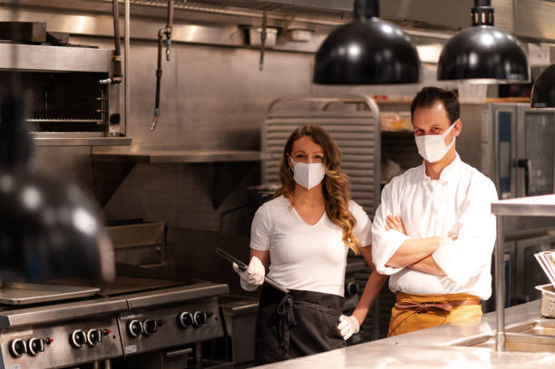 Hospitality team discussing bookings on a tablet Chefs and restaurant manager discussing reservations. Foodservice and hospitality workers. Hospitality after COVID. hygiene in restaurant kitchen stock pictures, royalty-free photos & images