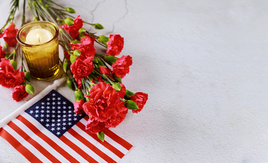 American flag and candle with red flowers carnation on white background. Memorial Day.
