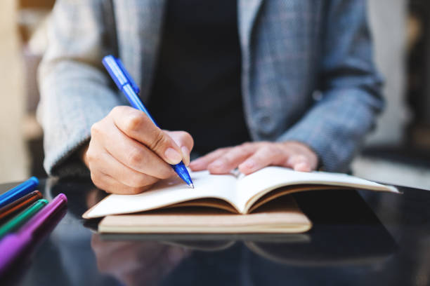 istock a woman writing on a blank notebook with colored pens on the table 1225147353