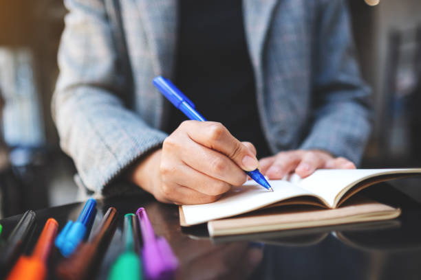 istock a woman writing on a blank notebook with colored pens on the table 1225147354