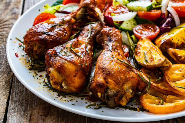 istock Roast chicken drumsticks and vegetables served on wooden table 1225151337