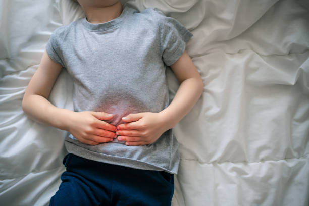 dolor abdominal en un niño en edad preescolar. intoxicación en niños. el niño sostiene sus manos a la cavidad abdominal - estreñimiento fotografías e imágenes de stock