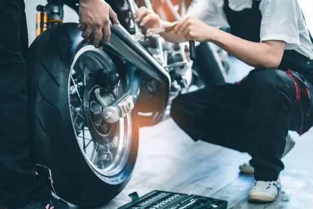 Photo of Bike repair. Young man repairing  motobike in garage.mechanic fixing motocycle engine.Serious young man repairing his motorcycle in bike repair shop.