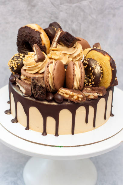 istock Peanut butter cake decorated with melted dark chocolate, donuts, chocolate bites, cake pops, macaroons and candies. 1225160151