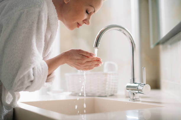 istock Young happy women in bathrobe wash her face. 1225167513