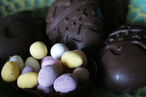 Stock photo showing dark chocolate easter egg shells filled with speckled candy coated chocolate mini easter eggs. The easter eggs were made by lining mould with melted plain chocolate which was then allowed to harden.