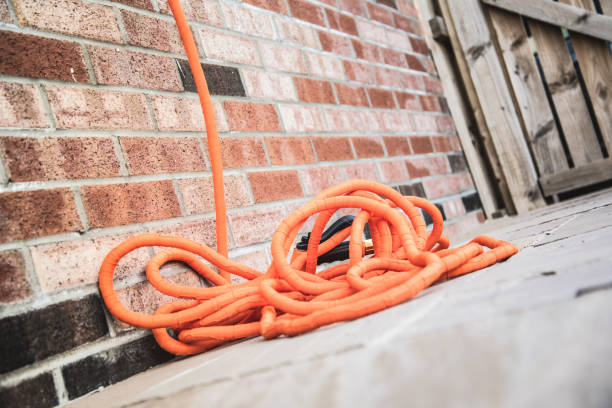 istock Orange extendable hose pipe on concrete floor in the garden next to brick wall 1225169971