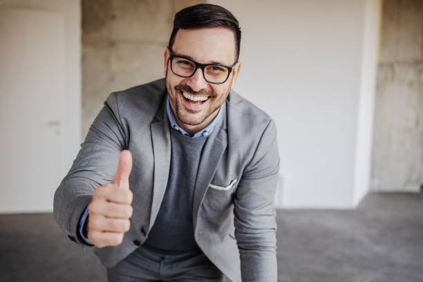 istock Young smiling businessman showing thumbs up. Building in construction process interior. 1225170094