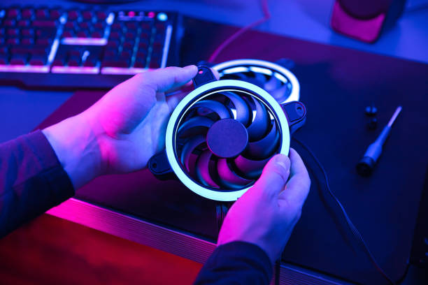 istock Man's hands hold modern computer fan with blue light with keyboard and speaker in the background. 1225177786