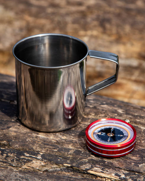 istock Tourist steel cup and compass in the summer forest 1225178019