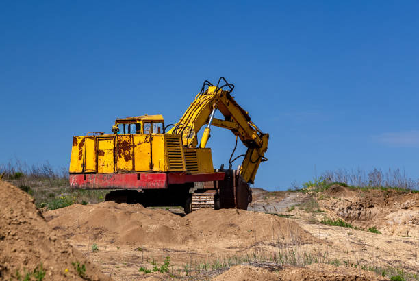 istock Yellow excavator during earthmoving at open pit on blue sky background. Construction machinery and earth-moving heavy equipment for excavation, loading, lifting and hauling of cargo on job sites 1225178328