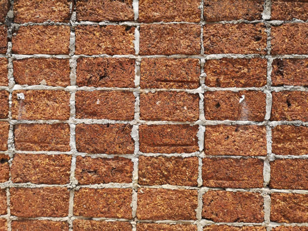 istock Red stone wall stacked up grout with grey cement Rock porous rough surface material texture background 1225179911
