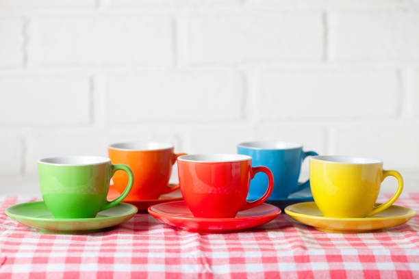Colorful cups on the white background of a brick wall. Background with copy space. Selective focus.