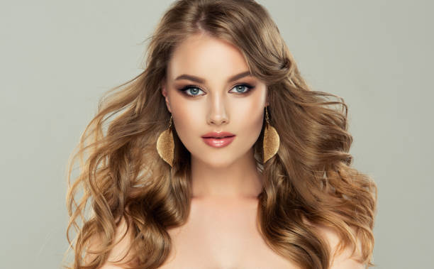 model with long, dense, freely laying hairstyle and neat makeup, leaf shaped golden earrings dressed in her ears - big hair blond hair frizzy women imagens e fotografias de stock