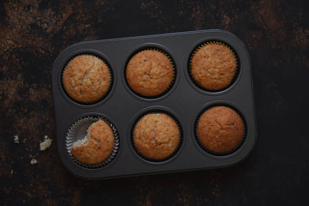 istock Banana muffins in baking dish on dark brown shabby background. 1225188440