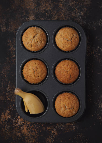 Banana muffins in baking dish on dark brown shabby background. Top view.