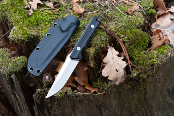 istock Knife with a fixed blade and plastic sheath on a stump. Stump and oak leaf. 1225191336